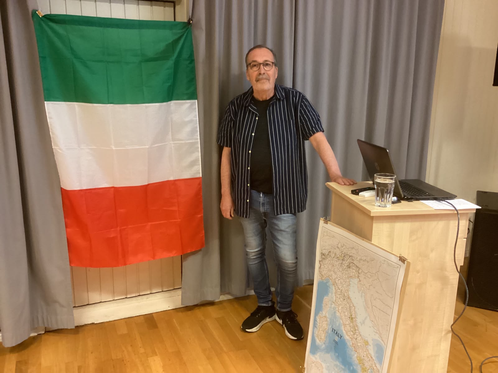 Bo Larsson bredvid en italiensk flagga och en karta över Italien